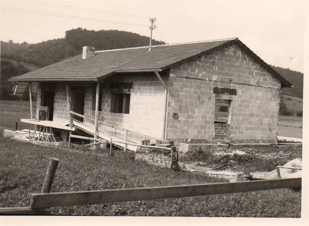 Das Vereinsheim 1968 im Rohbau: gemauerte Wände, Ziegeldach und ein Baugerüst, im Hintergrund bewaldete Hügel.