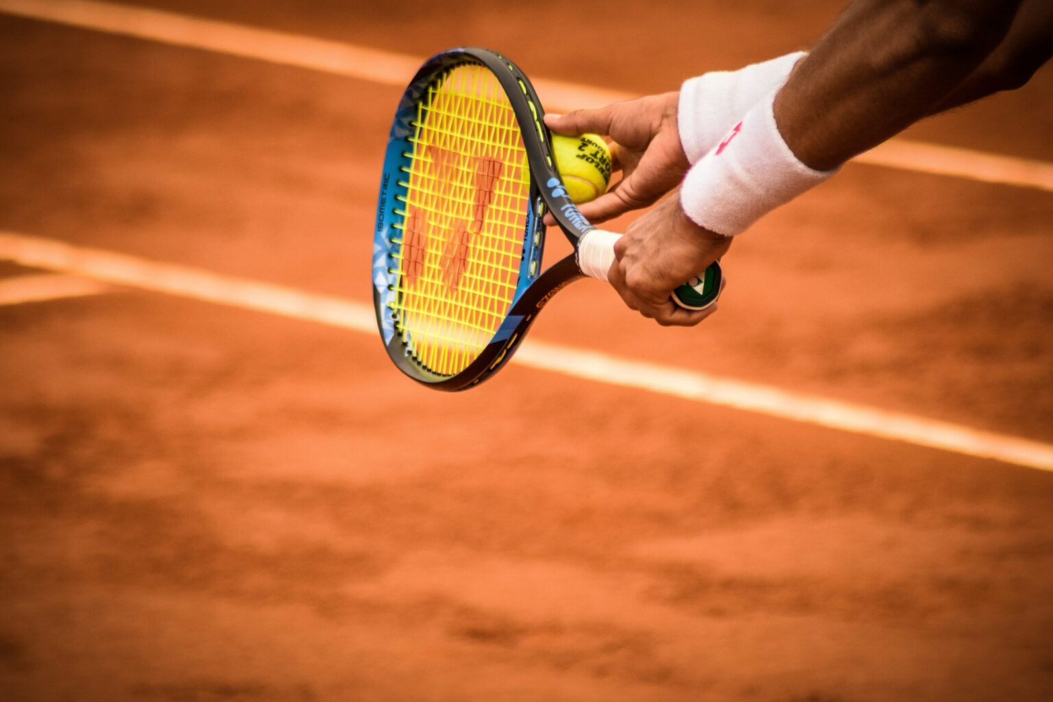 Tennisspieler hält Schläger und Ball und bereitet auf dem Sandplatz den Aufschlag vor